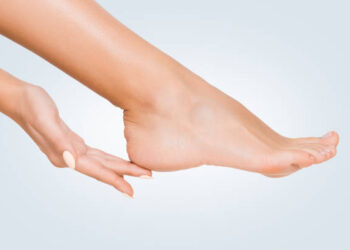 Perfect clean female feet . Woman touching her smooth heel, on blue background, closeup